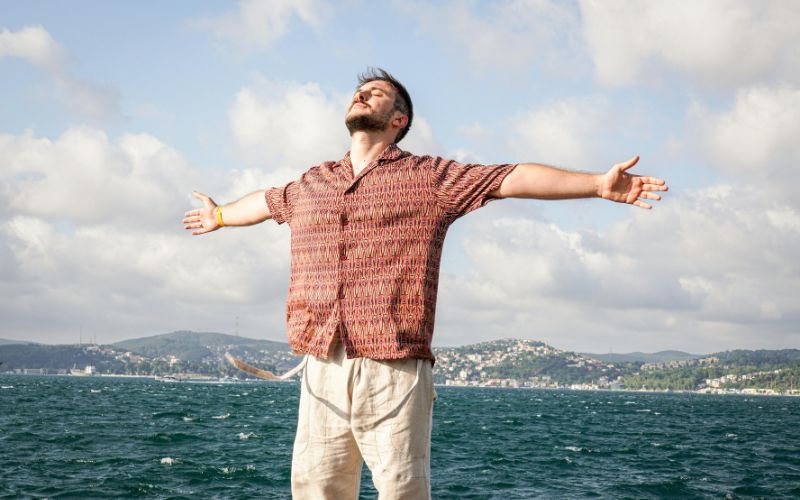 một người đàn ông đang đứng ngoài bãi biễn giang hai tay nói về vấn đề nhiều người thiếu hoạt động ngoài trời